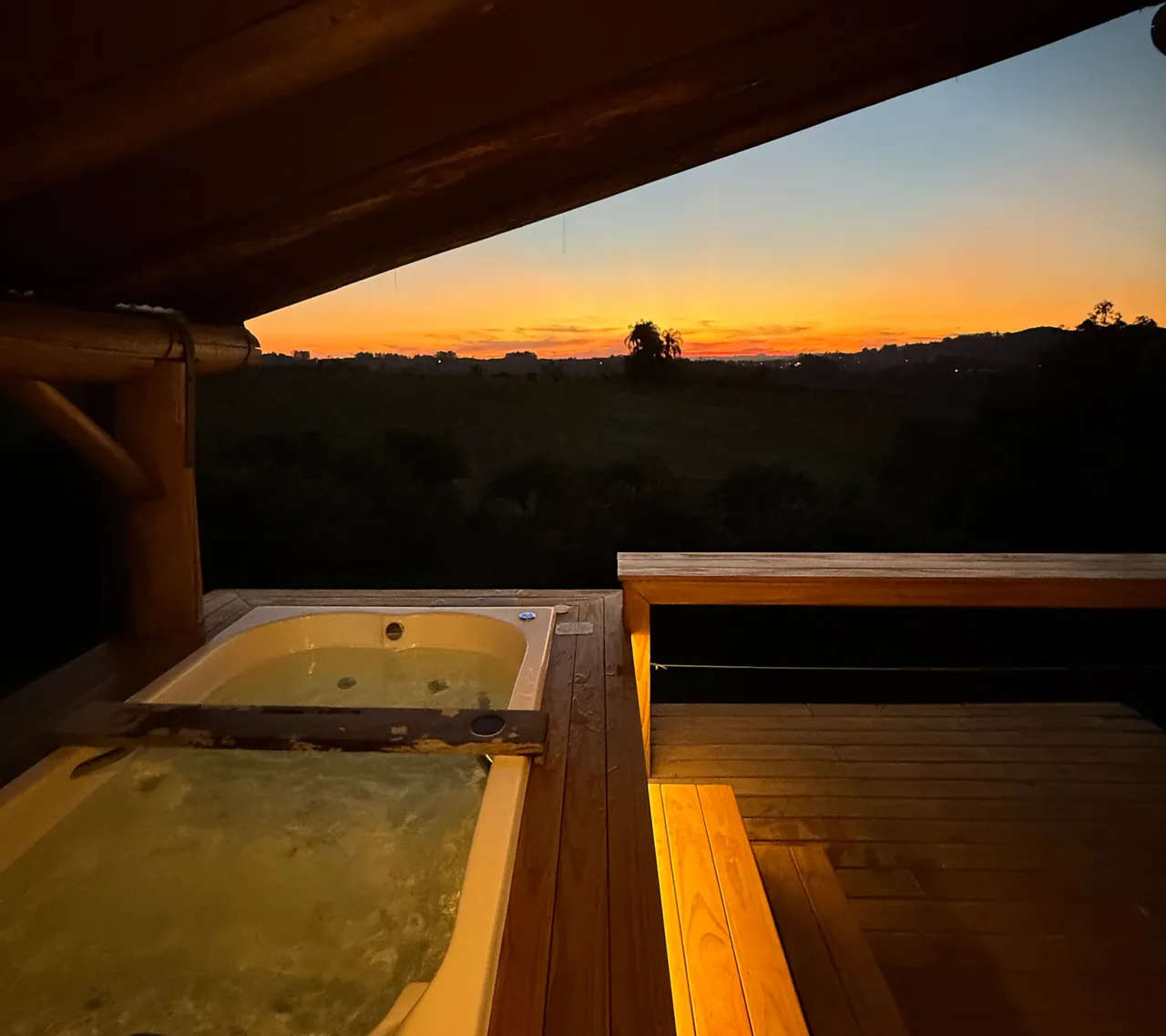 Jacuzzi na sacada ao entardecer, com o sol se pondo sobre o vale