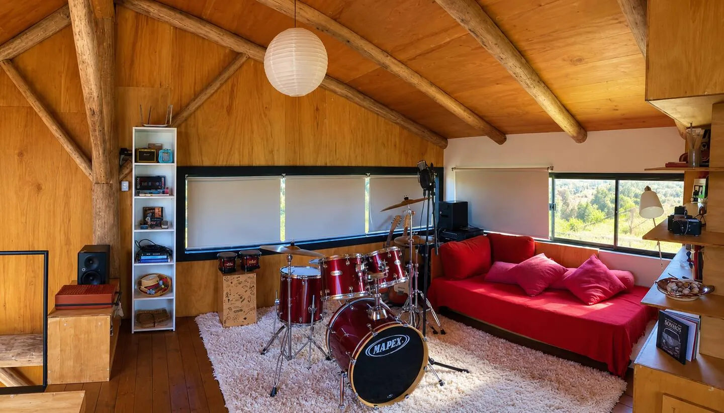 Studio musical no mezanino, com bateria e sofá vermelho