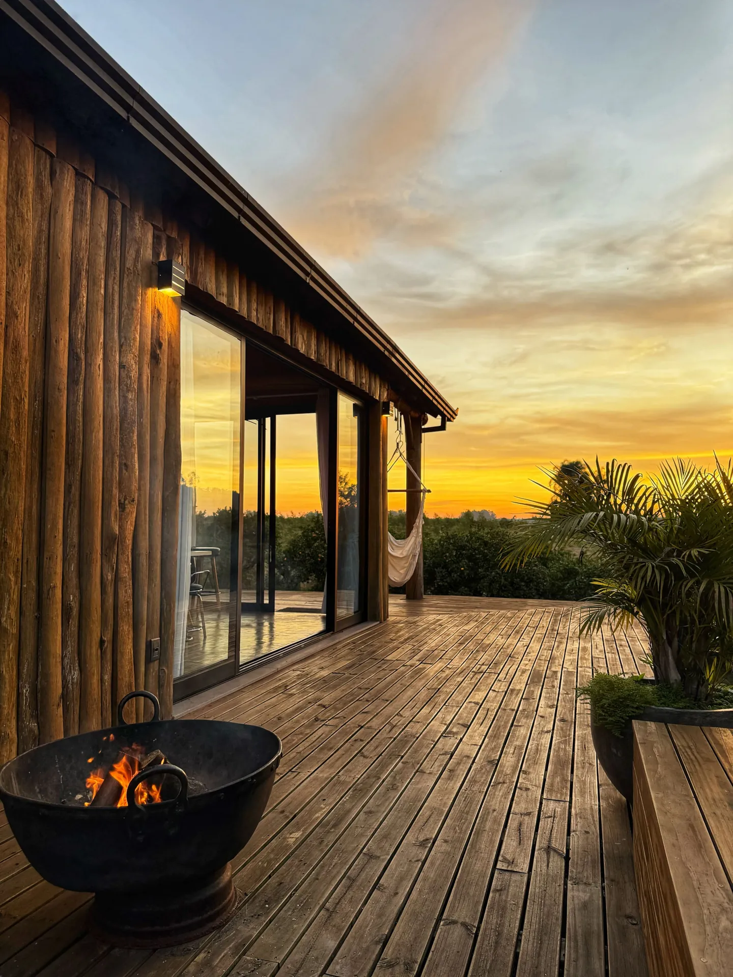Varanda de madeira com o fire pit aceso ao pôr do sol